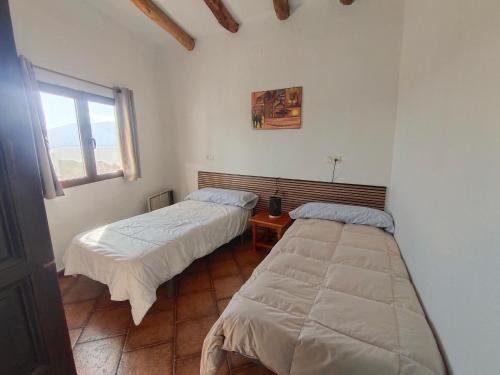 deux lits dans une chambre avec fenêtre dans l'établissement Casa Mirador, à Cáñar