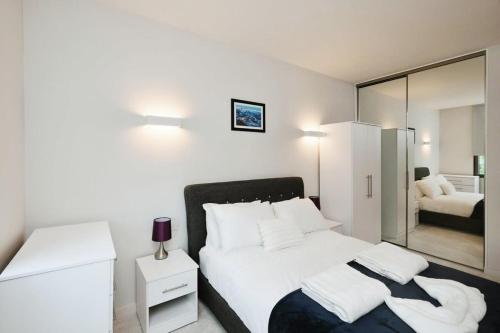 a bedroom with a large white bed and a mirror at Modern 1 Bed Apt Bracknell- with parking in Bracknell