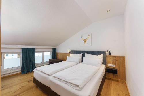 a bedroom with a large bed with white sheets at Appartements Landhaus Hubertus Wellness & Breakfast in Schladming