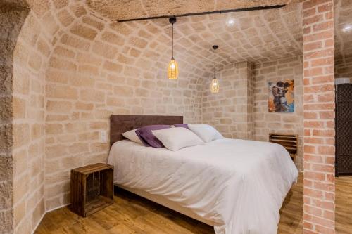 Un dormitorio con una cama en una pared de ladrillos. en La voûte des Baous, en Vence