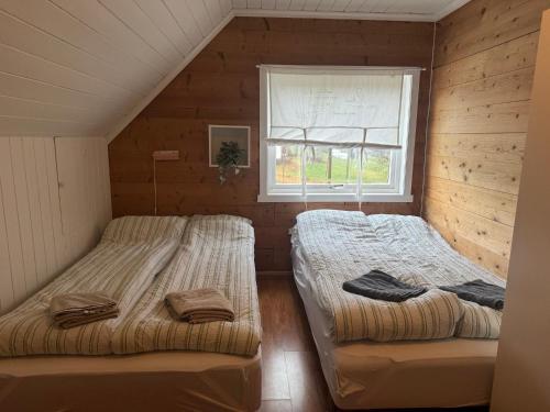 two beds in a room with a window at Superkoselig familiehus med lekerom - Barnevennlig in Vossevangen