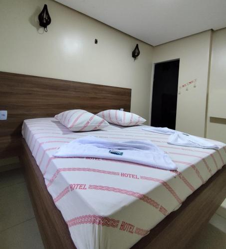 Cama grande con sábanas y almohadas rosas y blancas en Hotel-Motel Novo Oasis, en São Paulo