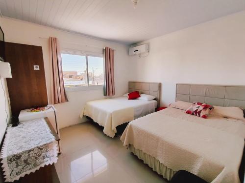 Camelo locação de Suítes Individuais Pousada com Cozinha e Sala Compartilhada في أرويو دو سيلفا: غرفة فندق بها سريران ونافذة