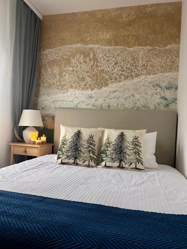 a bed with four pillows with trees on it at Apartament w Słupsku centrum bezpłatny parking in Słupsk