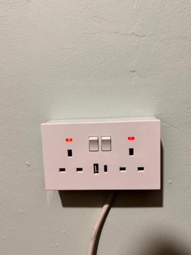a white electrical outlet on a wall with a wire at Stylish Room in Central London! in London