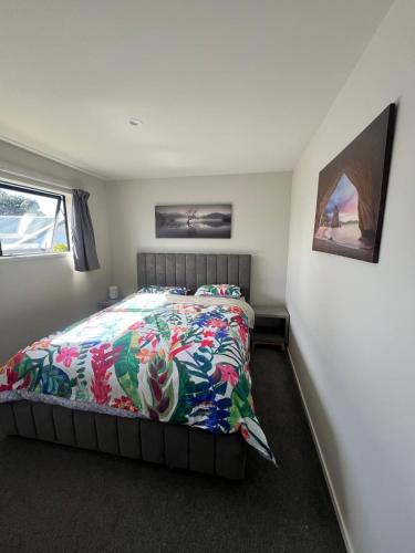 a bedroom with a bed with a colorful comforter at Sun and fun in the Bay - Home away from Home in Porirua