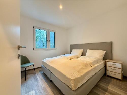 um quarto com uma cama, uma cadeira e uma janela em Treehouse - Alpinlake Apartments em Grünau im Almtal