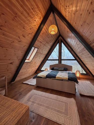 un letto in una camera con una grande finestra di Transilvania Chalet a Zărneşti