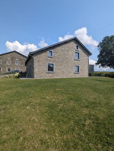 a large brick house on a grassy field at La Petite Reine in Bertrix