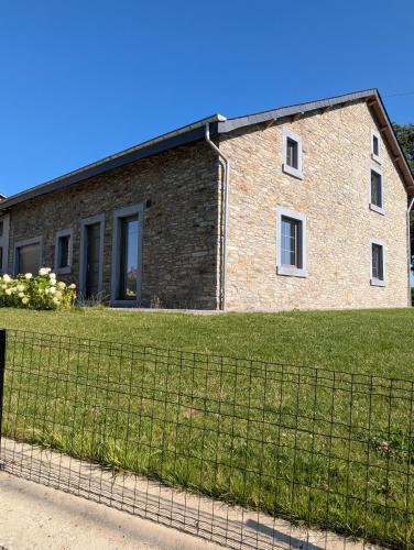 a brick building with a fence in front of it at La Petite Reine in Bertrix