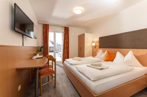 a hotel room with a bed with a desk and a television at Erlys Cityhotel in Schladming