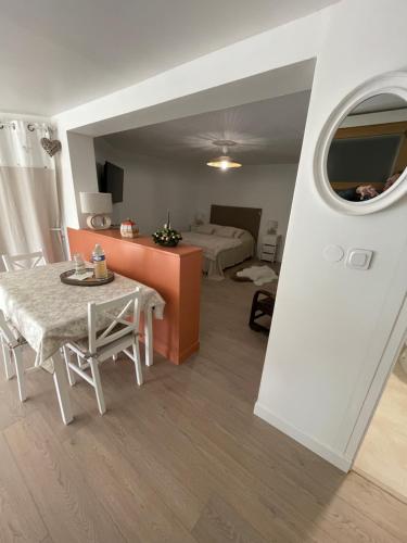 a living room with a table and a bedroom at À la clef des champs in Chauray