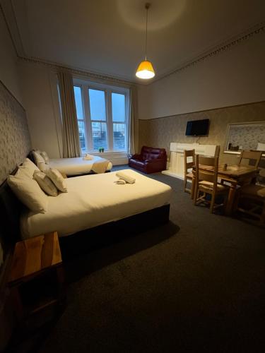 a hotel room with two beds and a dining room at Piccolo Guest House in Glasgow