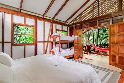 Private Villa with Pool & Heated Jacuzzi, AC, Jungle Garden Near Amenities & Beach في Talamanca: غرفة نوم بها سرير وأرجوحة فيها