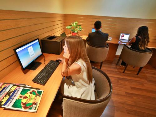 a woman sitting at a table with a laptop computer at Lancaster Tamar Hotel- Hadath in Beirut