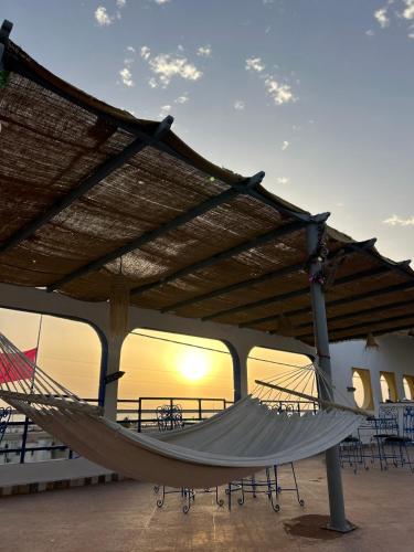 a hammock under a roof with tables and chairs at arganier solitaire in Souira Guedima