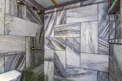 a bathroom with a shower with a stone wall at Mountain Top Cabin with a View - Bear Cabin in Ruidoso