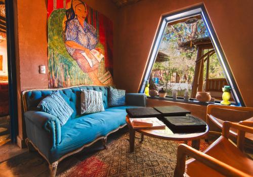 Ckoi Atacama Lodge في سان بيدرو دي أتاكاما: غرفة معيشة بها أريكة زرقاء ولوحة كبيرة