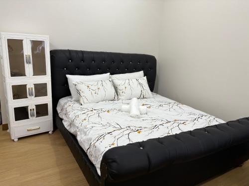 G-VibeZzz Staycation في Trece Martires: سرير أسود عليه دمية دب