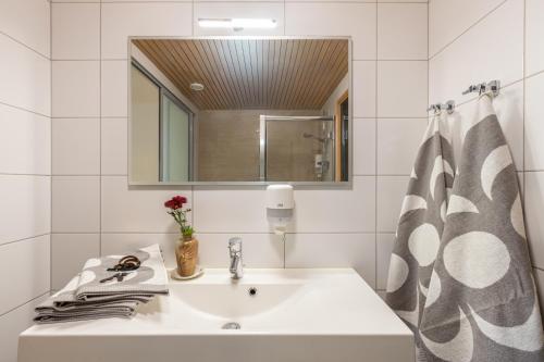 a white bathroom with a sink and a mirror at RUF studio Naantali- Unique design apartment in Naantali