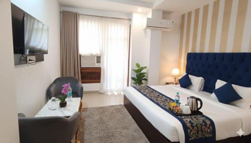 Una habitación de hotel con una cama, una silla y un televisor. en Hotel Lime Pride Park Near By IGI Airport Delhi, en Nueva Delhi
