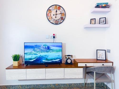 a tv on a cabinet with a clock on the wall at Five-Eight Residences in Jinja