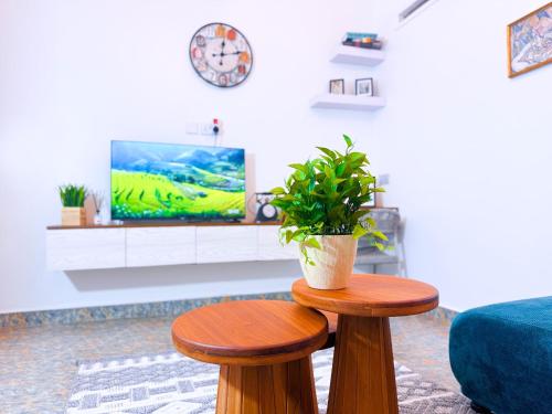 a living room with two wooden stools and a tv at Five-Eight Residences in Jinja