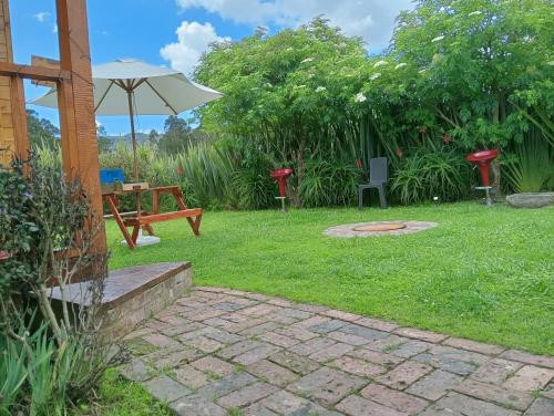 a garden with a picnic table and an umbrella at Cabaña Los Linos in Guasca