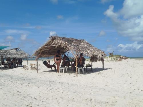 Un grupo de personas sentadas bajo una sombrilla de paja en la playa. en La foca da Croa, en Goiana