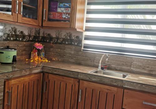 Una cocina con armarios de madera y un fregadero y una ventana. en S And K Holiday Stay, en Beruwala