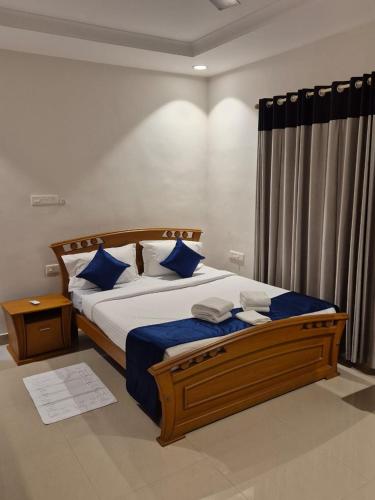a bedroom with a large bed with blue pillows at Invito Beach Resort in Kannur