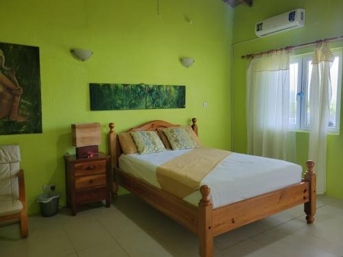 Schlafzimmer mit einem Bett mit grünen Wänden und einem Fenster in der Unterkunft A Serene Get Away in Vieux Fort