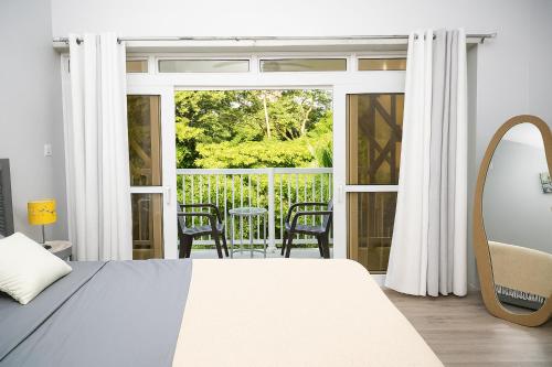 a bedroom with a bed and a balcony with a table and chairs at La Retraite Apt in Rodney Bay Village