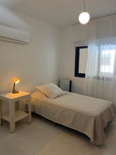 a bedroom with a bed and a table with a lamp at HABITACIÓN en VILLA ALLENDE, north green in Villa Allende
