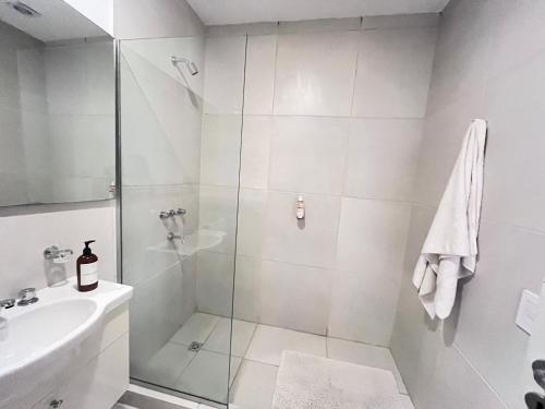 a white bathroom with a shower and a sink at HABITACIÓN en VILLA ALLENDE, north green in Villa Allende