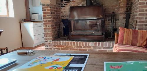 sala de estar con chimenea de ladrillo y fogones en Gîte la petite maison, en Pontchardon