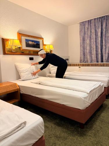 a man making a bed in a hotel room at Yeti City Hotel Saarbrücken in Saarbrücken