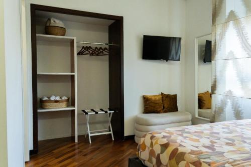 a bedroom with a bed and a chair and a television at ROOMITO apartments in Naples