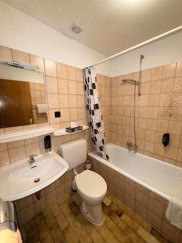 a bathroom with a toilet and a sink and a tub at Yeti City Hotel Saarbrücken in Saarbrücken
