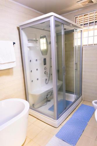 a bathroom with a shower and a toilet and a tub at Mirembe Villas Kigo in Kigo