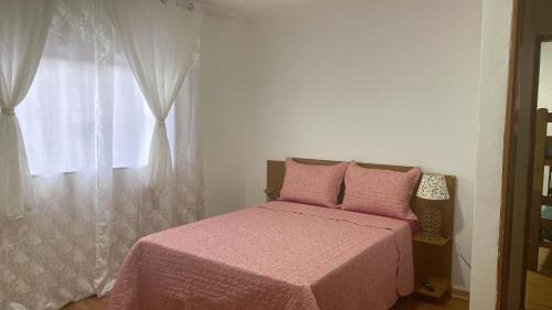 een slaapkamer met een roze bed en een raam bij Casa piscina in Poços de Caldas