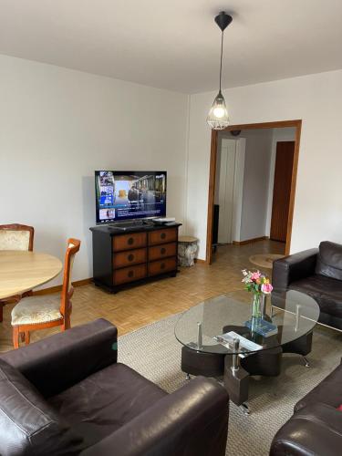 un soggiorno con un divano, un tavolo e una TV di Champs Bernard a Villefranche-de-Rouergue