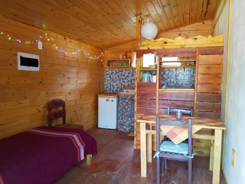 a room with a table and a bed in a cabin at Chalets rustiques en pleine nature, L'ARCHIPEL in Punta Del Diablo