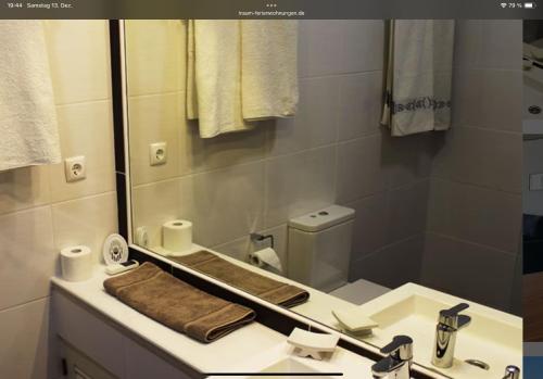 een badkamer met een wastafel met een spiegel en een toilet bij Casa Bele Algarve in Ferragudo