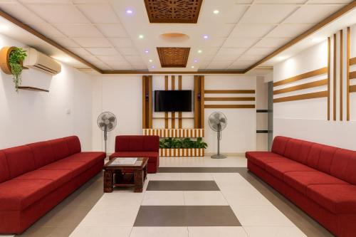 een wachtkamer met rode banken en een flatscreen-tv bij Baral White Rose Hotel in Dhaka