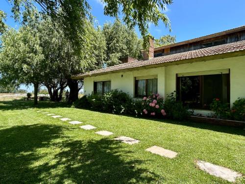 una casa con un patio con césped y árboles en Casa Quinta El Refugio, en Villa Gesell