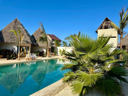 een resort met zwembad en palmbomen bij GARDEN EDEN Lodge in Jambiani