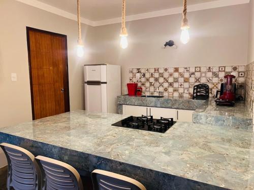 バイーア・フォルモーザにあるCasa Fundo de Quintalのキッチン(椅子とコンロ付きのカウンター付)