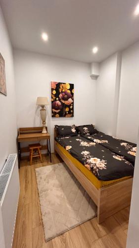 a bedroom with a bed and a table and a painting at Miodowy apartament in Chorzów