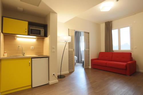 a living room with a red couch and a kitchen at Westlodge Dardilly Lyon Nord in Dardilly